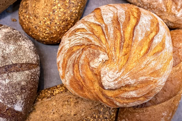 Round loaf of bread on background of different bread loaves. Bread collection top view background.