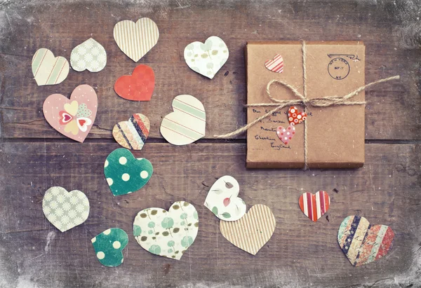 Un regalo sobre fondo de madera con corazones — Foto de Stock