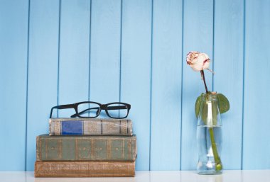 Books pile, glasses and white rose in the bottle clipart