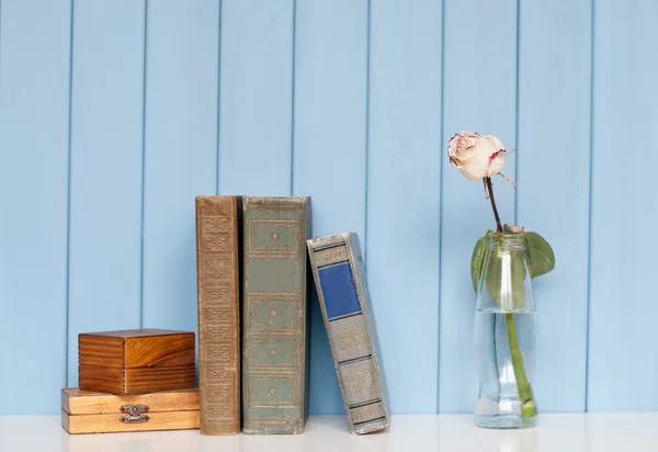 Livros pilha, duas caixas de madeira e rosa branca na garrafa — Fotografia de Stock