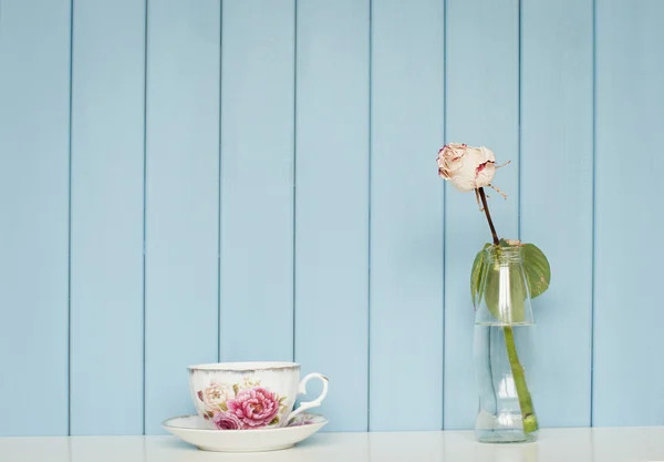 Cup of tea and white rose in the bottle — Stock Photo, Image