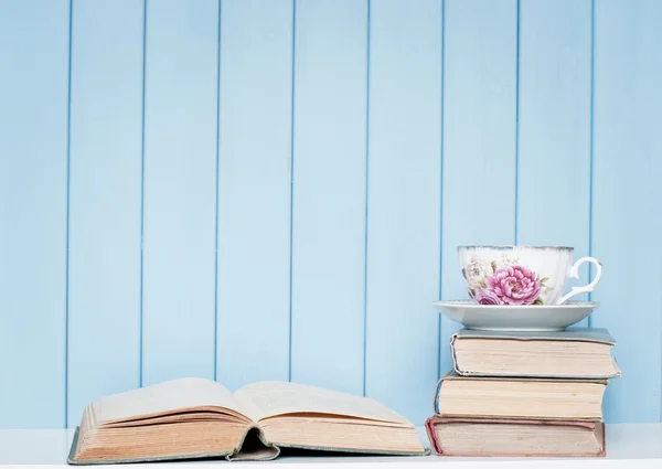 Livros antigos, copos e xícara de porcelana na estante — Fotografia de Stock