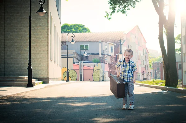 Liten unge hålla resväskan och gick nedför sundblad — Stockfoto