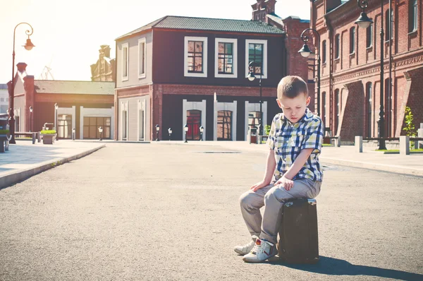 伤心的小男孩正坐在行李箱上 — 图库照片