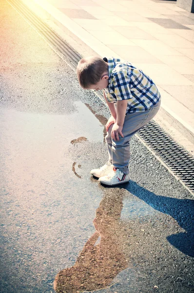 Little boy is looking at the puddle — Stock Photo, Image
