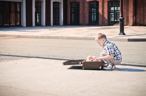 Little kid is openingthe suitcase on the sunny street — Stock Photo, Image