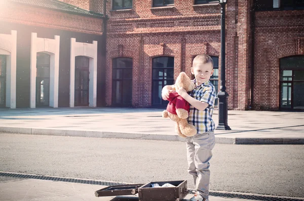 Pequeño niño está sosteniendo peluche oso juguete en la calle soleada —  Fotos de Stock