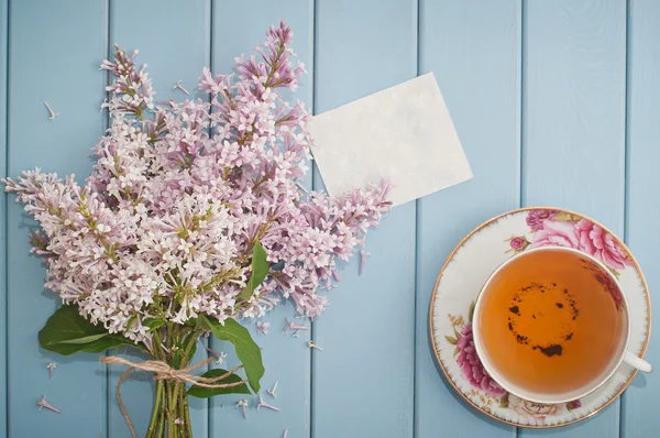 Summer bouquet of gentle blooming lilac with card and tea — Stock Photo, Image