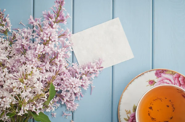 Summer bouquet of gentle blooming lilac with card and tea — Stock Photo, Image