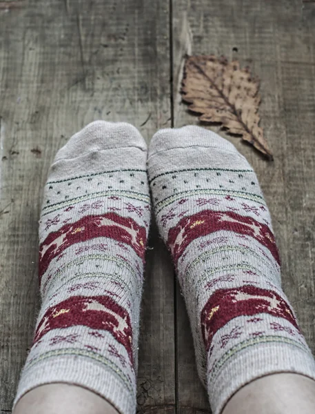 Feet in knitted woolen socks and oak leaf — Stock Photo, Image