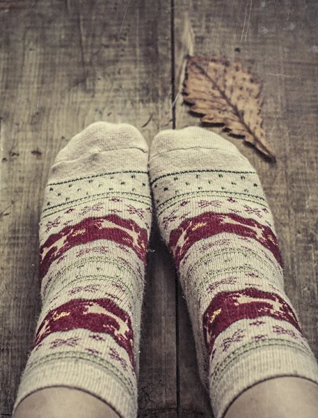 Feet in knitted woolen socks and oak leaf — Stock Photo, Image