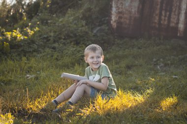 Çimenlerin üzerinde oturan küçük boy gülümseyerek