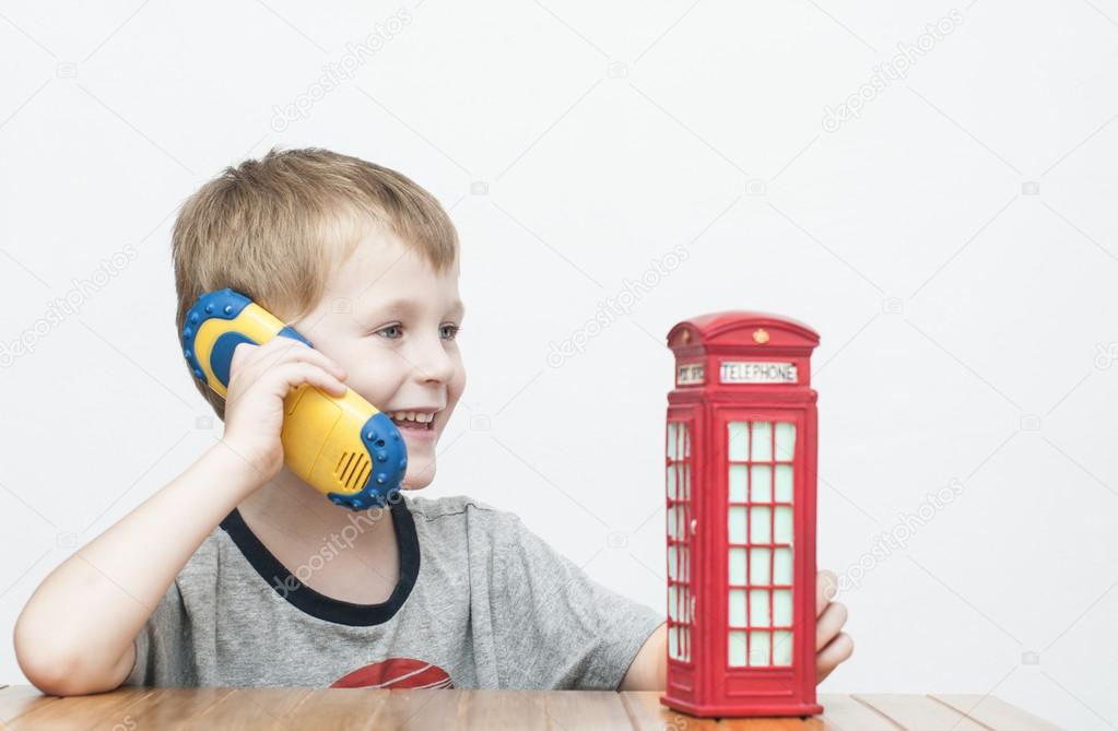 Boy talking on the phone and red telephone booth