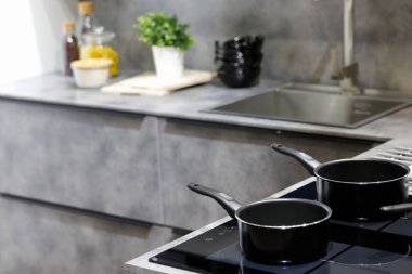 Modern kitchen with non-stick saucepans on an induction stove. Selective focus. clipart