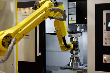 Robot kol CNC makinesine bir iş parçası yüklüyor. Seçici odak.