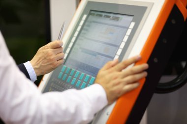 Endüstriyel eğitim. Mühendis CNC kontrol paneli kullanarak yeni bilgisayar imalat ekipmanları üzerinde çalışmayı öğretiyor. Seçici odak.