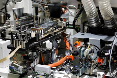 Closeup of pneumatic and electrical components of automatic edge banding machine. Selective focus.