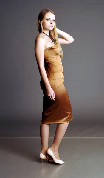 Schöne Blondine in einem goldenen Kleid — Stockfoto