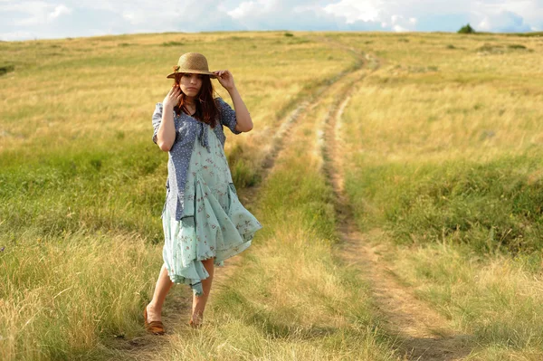 Girl in a straw hat, wind in the field — Stock Photo, Image