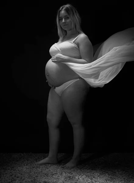 Pregnancy session in the studio. The pregnant woman. A pair of young future parents.