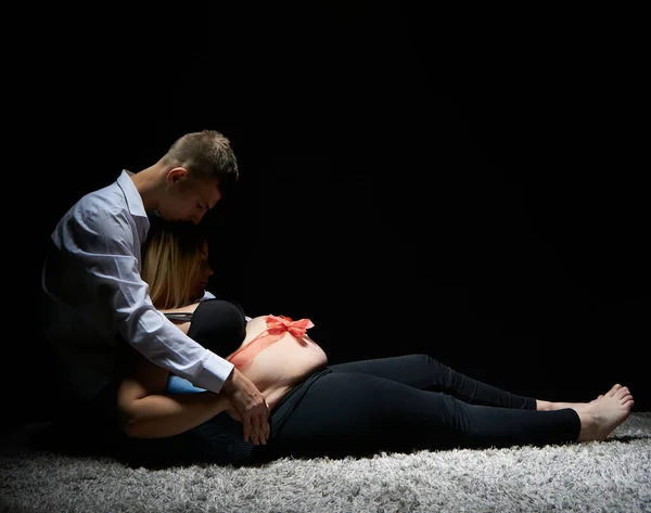 Pregnancy session in the studio. The pregnant woman. A pair of young future parents.