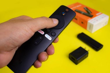 İçinde şarj aleti, uzaktan kumanda, mikro usb kablosu ve el kitapları olan android TV çubuğu..