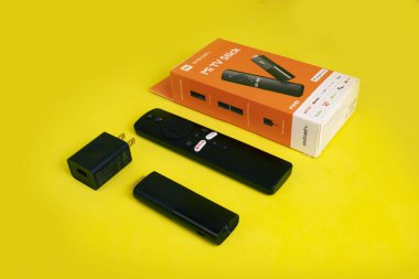 İçinde şarj aleti, uzaktan kumanda, mikro usb kablosu ve el kitapları olan android TV çubuğu..