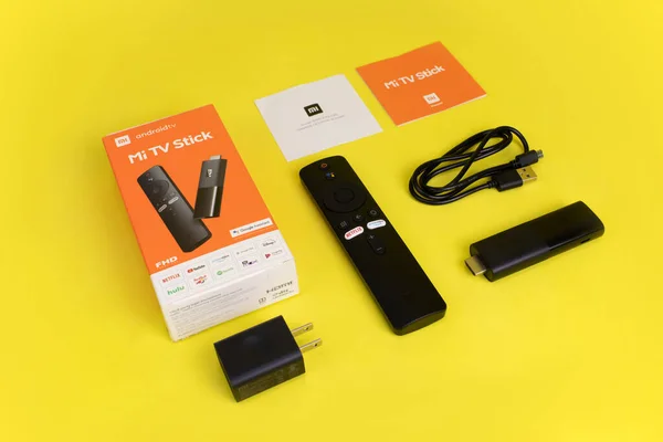 İçinde şarj aleti, uzaktan kumanda, mikro usb kablosu ve el kitapları olan android TV çubuğu..