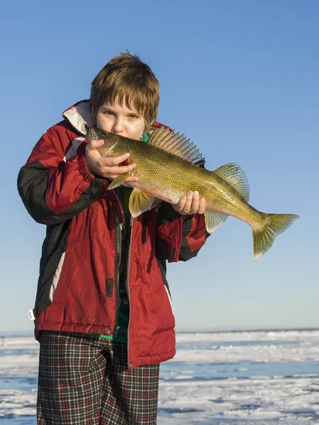 Een jonge ijs visser met een grote snoekbaarzen — Stockfoto