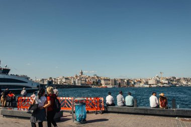 ISTANBUL, TURKEY - NOVEMBER 12, 2020: People on coastline with sea and buildings at background  clipart