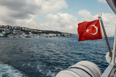 Turkish flag on ship in sea with seafront at background, Istanbul, Turkey  clipart