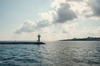 Denizdeki iskelede deniz feneri ve İstanbul, Türkiye 'de arka planda bulutlu gökyüzü 