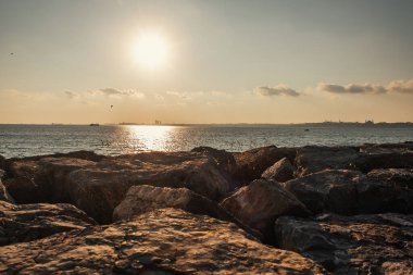Gün batımında deniz kıyısındaki taşların manzarası