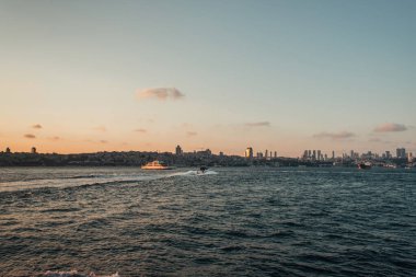 Arka planda kıyı ve günbatımı gökyüzü olan deniz yatı, İstanbul ve Türkiye 