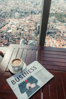 Kahve fincanı ve iş gazetesi, İstanbul-Türkiye manzaralı kafe masasında.