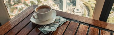 Kafe 'de, İstanbul manzaralı ahşap masa üzerinde bir fincan kahve ve dolar, pankart.