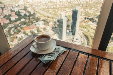 İstanbul manzaralı kafeterya penceresinin yanında dolar ve bir fincan kahve.