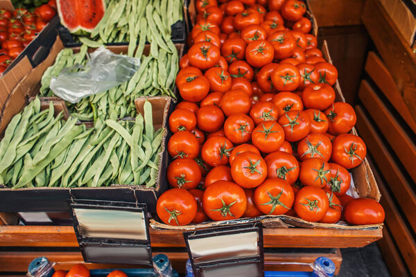Fresh tomatoes and green beans on counter of outdoors market