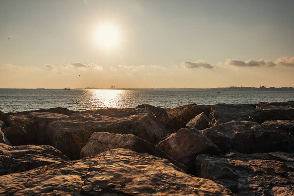 Scenic view of stones on coast of sea during sunset