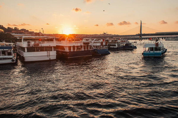 Moored boats near coastline and Golden horn metro bridge with sunset sky at background, Turkey 