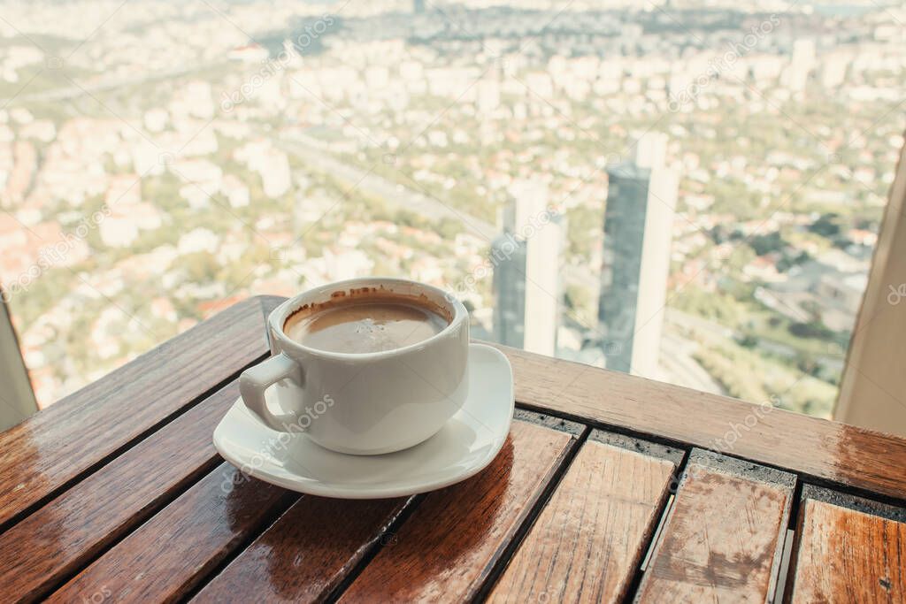 cup of coffee on wooden table near window with aerial view of Istanbul