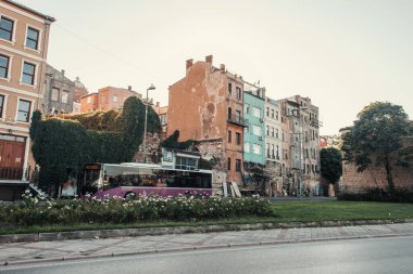 İSTANBUL, TÜRKEYE - 12 Kasım 2020: Bina yakınında çiçek bahçesi ve otobüs, caddede yeşil sarmaşıklarla kaplı 