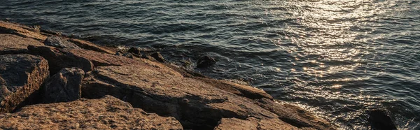 Piedras en la costa del mar durante la puesta del sol, bandera - foto de stock