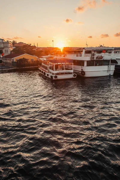 Bots amarrés près des bâtiments sur la côte de la ville et le coucher du soleil en arrière-plan, Istanbul, Turquie — Photo de stock