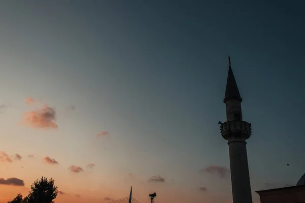 Vista de ángulo bajo de la columna de la mezquita Mihrimah Sultan y el cielo durante la puesta del sol en el fondo, Estambul, Turquía - foto de stock