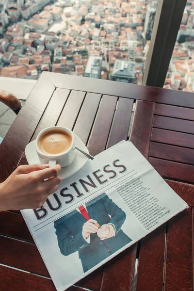 Vista recortada del hombre cerca de taza de café y periódico en la cafetería con vista aérea de Estambul - foto de stock