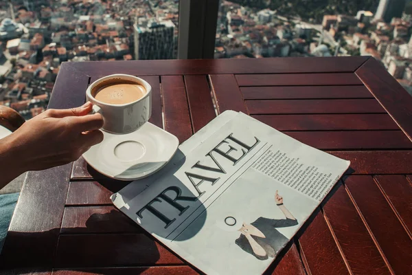 Vue recadrée d'un homme tenant un café près d'un journal de voyage dans un café avec vue aérienne d'Istanbul — Photo de stock