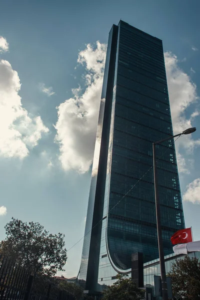 Drapeau turc, lanterne et arbres près du gratte-ciel contre un ciel nuageux à Istanbul, Turquie — Photo de stock