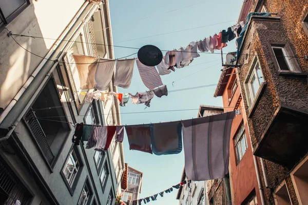 Vista de ángulo bajo de tendedero con lavandería entre casas en calle estrecha en el barrio de Balat, Estambul, Turquía - foto de stock