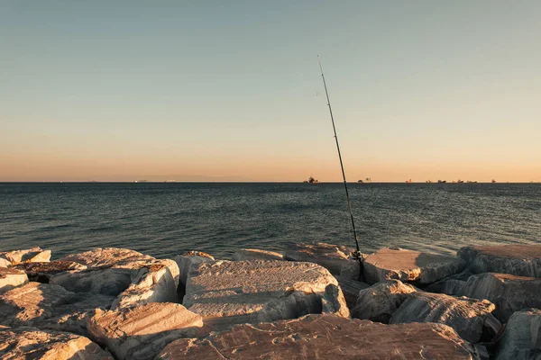Caña de pescar en piedras en la orilla del mar - foto de stock